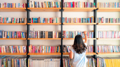 Woman in a library getting books of a bookshelf